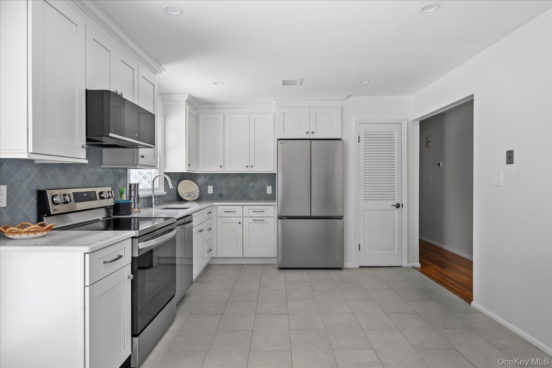 64 Old Depot Road Quogue, NY 11959 - Photo 11 of 14 a kitchen with a refrigerator a stove top oven a sink and cabinets
