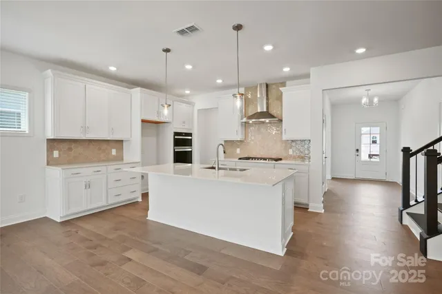 a large white kitchen with lots of counter space a sink appliances and cabinets