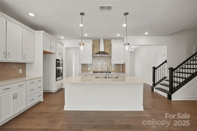 a large kitchen with stainless steel appliances kitchen island granite countertop a refrigerator and a stove top oven