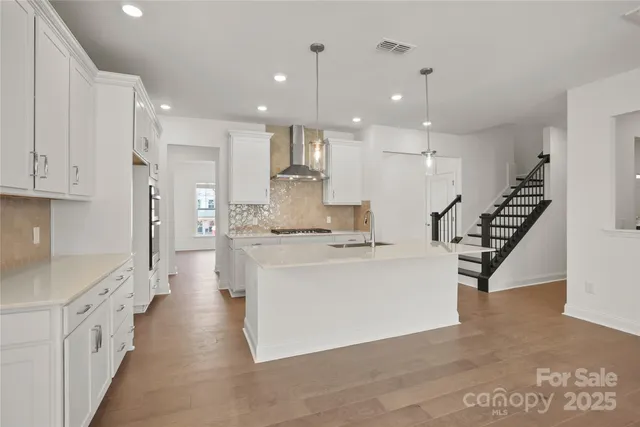 a large white kitchen with lots of counter space wooden floor and stainless steel appliances