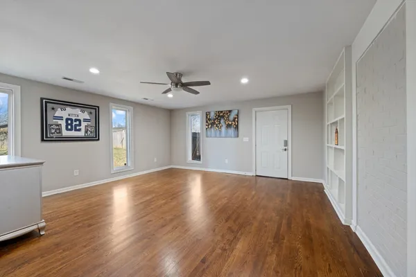 a view of an empty room with wooden floor and a window