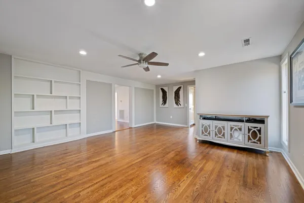 a view of an empty room with a window and wooden floor