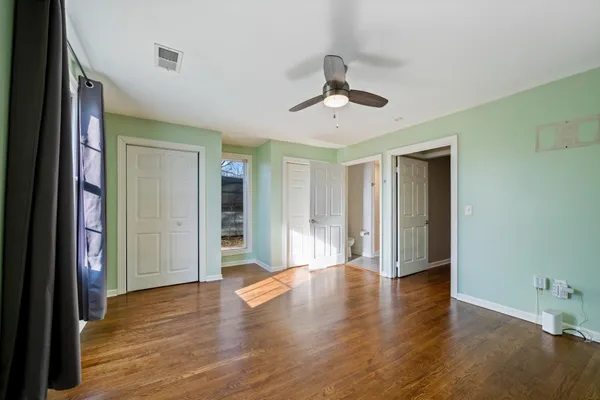 a view of an empty room with wooden floor and closet area