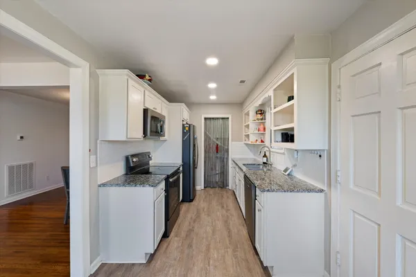 a kitchen with stainless steel appliances granite countertop lots of counter top space and wooden floor