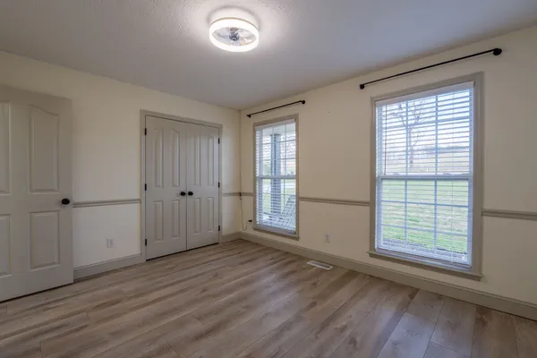 an empty room with wooden floor and windows