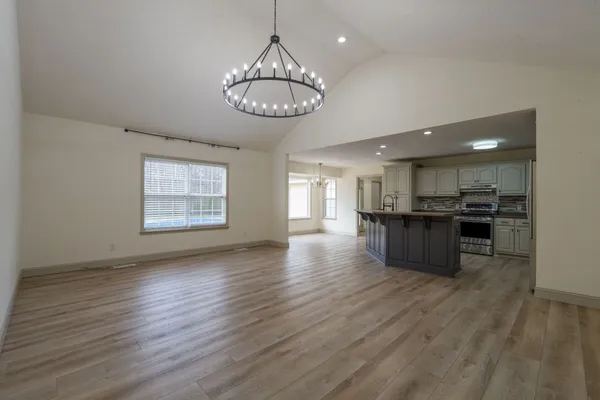 an open kitchen with a refrigerator and wooden floor