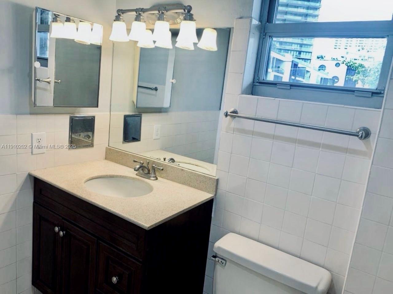 555 Northeast 30th Street, Unit 203 Miami, FL 33137 - Photo 13 of 23 a bathroom with a sink vanity mirror and toilet