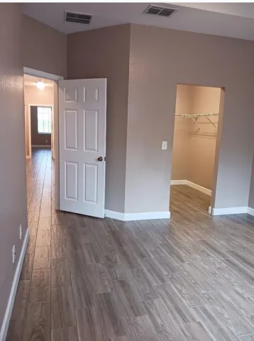 a view of an empty room with wooden floor and closet