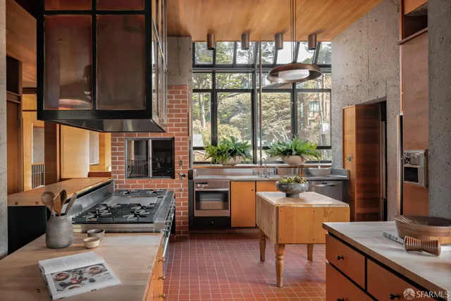 a kitchen with stainless steel appliances a stove a sink cabinets and a dining table view