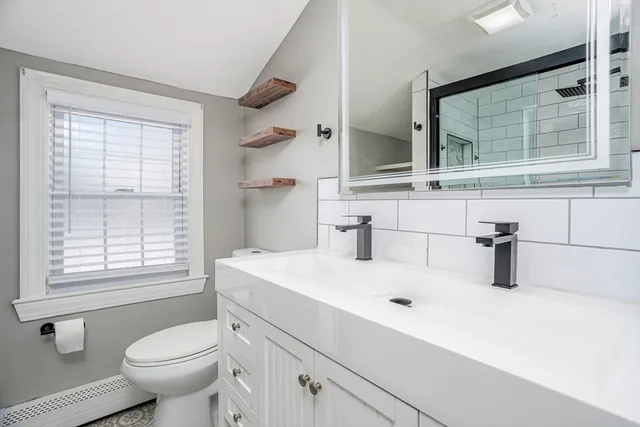 a bathroom with a sink toilet vanity and window