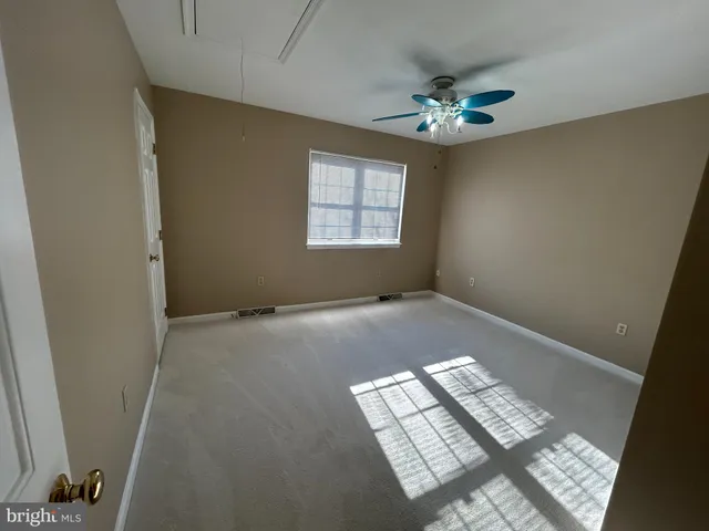 a view of an empty room and chandelier fan