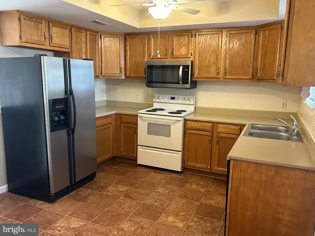 a kitchen with granite countertop a refrigerator and a stove top oven