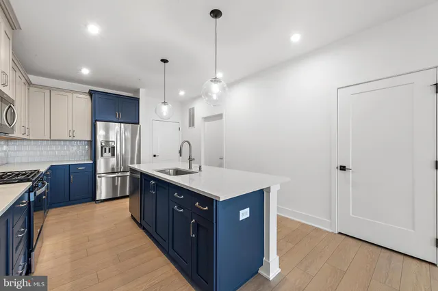 a kitchen with a stove a sink a refrigerator and wooden floor