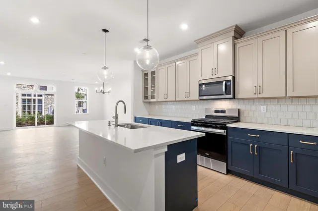 a kitchen with stainless steel appliances granite countertop a sink a stove and a wooden floors