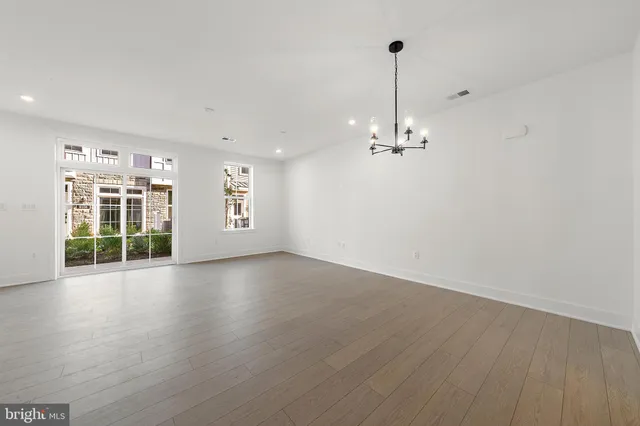 a view of a room with wooden floor chandelier and windows