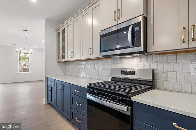 a kitchen with stainless steel appliances a stove a microwave cabinets and a wooden floor