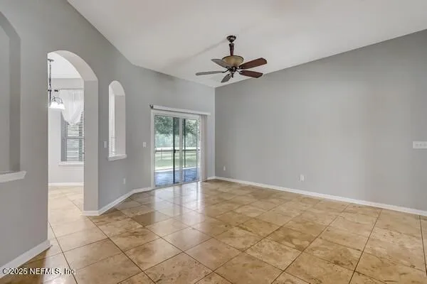 a view of an empty room with wooden floor and a ceiling fan