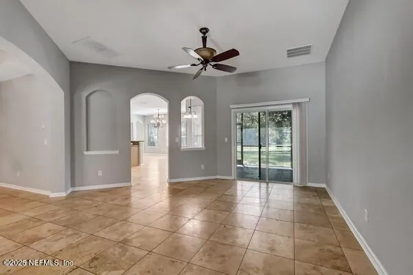 a view of an empty room with window and a ceiling fan