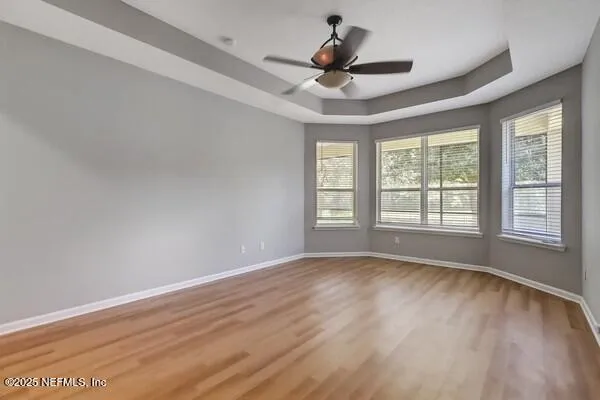 a view of an empty room and window with a chandelier fan