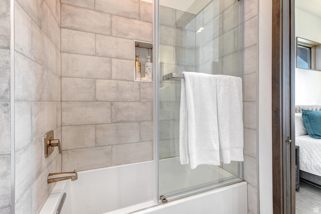 1282 Chimney Rock Road, Unit 344 Heber City, UT 84032 - Photo 43 of 55 Bathtub with subway tile surround, integrated shower niche, brushed bronze fixtures, and a clear glass shower enclosure