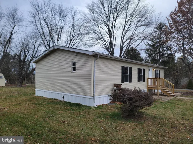 a backyard of a house with wooden fence and large tree