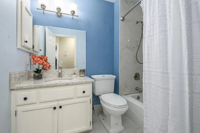a bathroom with a granite countertop sink a toilet and a mirror