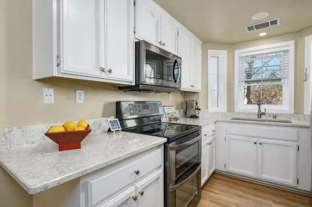 a kitchen with stainless steel appliances granite countertop a sink stove and cabinets