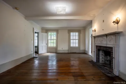 an empty room with wooden floor fireplace and windows