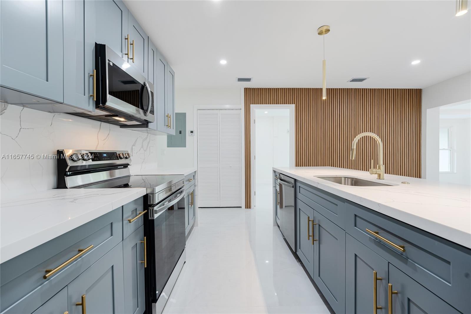 4802 Northwest 11th Avenue Miami, FL 33127 - Photo 7 of 26 a kitchen with stainless steel appliances a sink a stove oven a refrigerator with white cabinets and a wooden floor