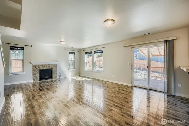 a view of an empty room with window and wooden floor