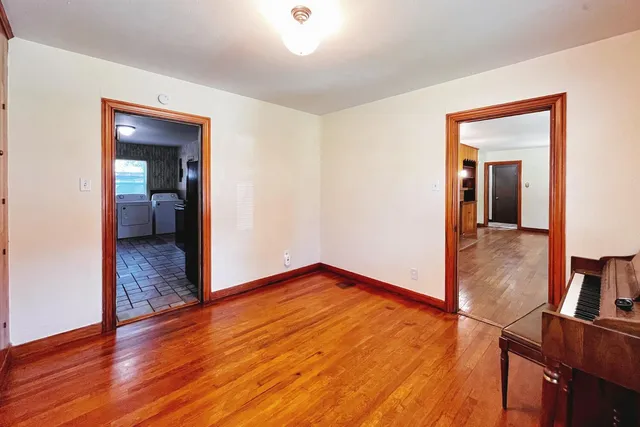 a view of a hallway with wooden floor and a bathroom