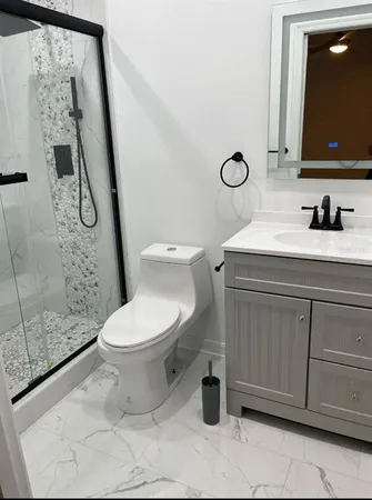 a bathroom with a granite countertop toilet sink and mirror