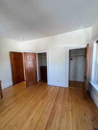 a view of an empty room with closet and a window