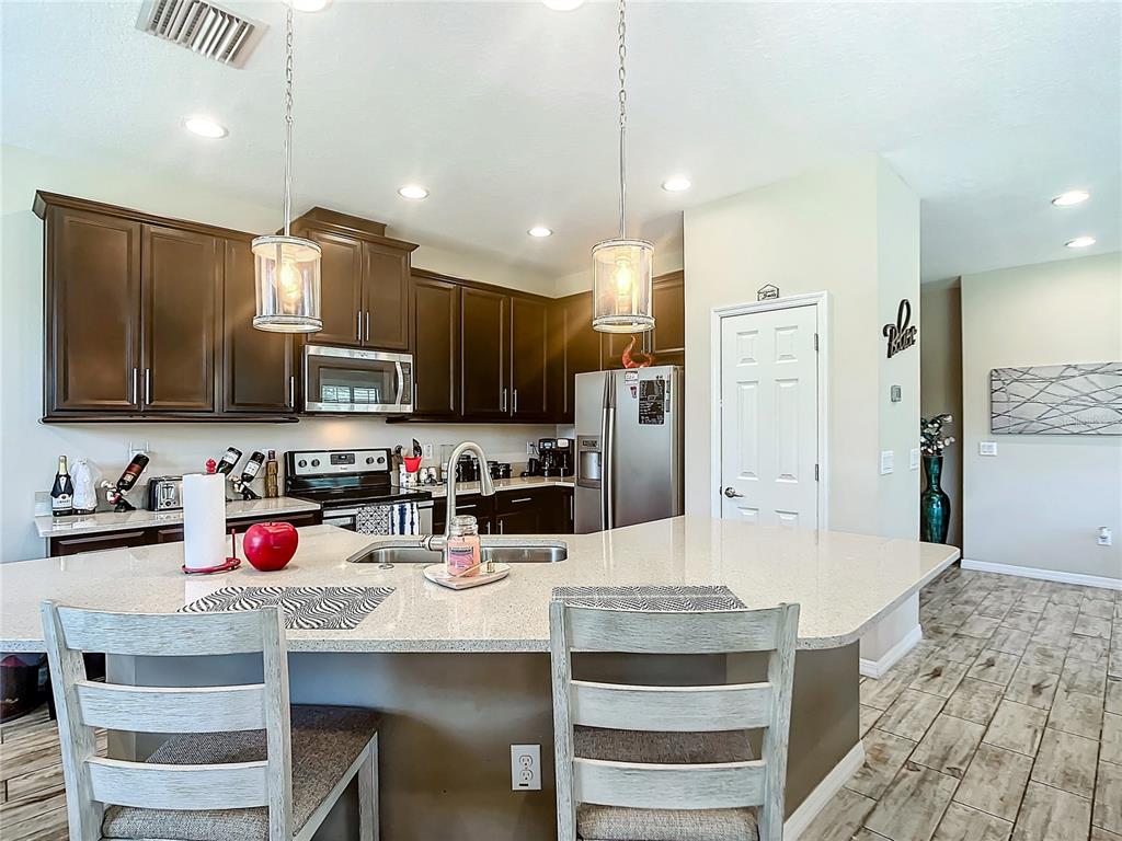 4744 Wandering Way Wesley Chapel, FL 33544 - Photo 13 of 39 a kitchen with kitchen island granite countertop a sink and wooden cabinets