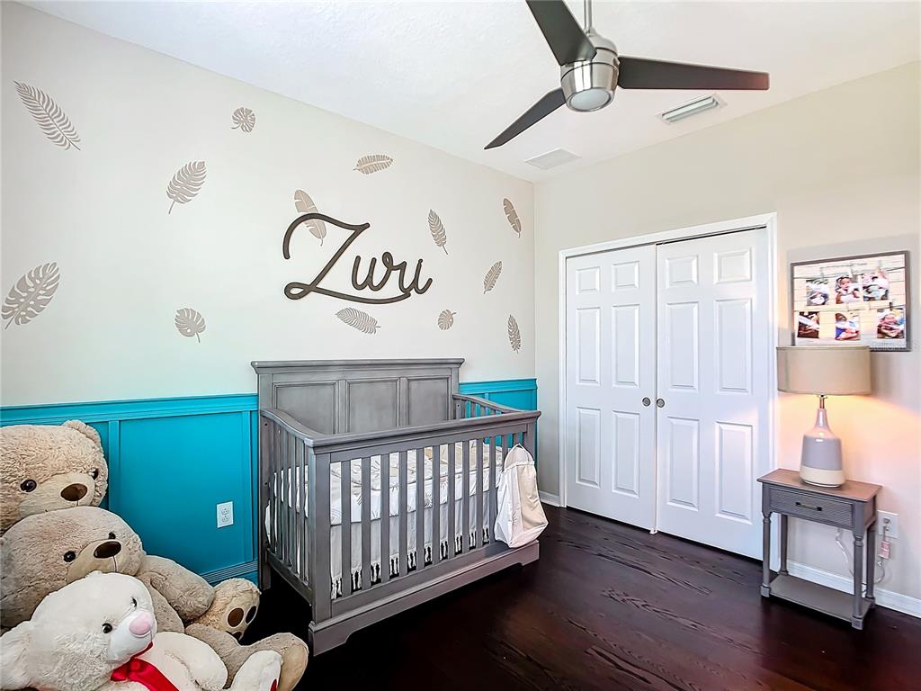 4744 Wandering Way Wesley Chapel, FL 33544 - Photo 23 of 39 a bedroom with baby crib and wooden floor