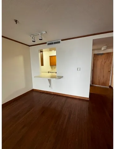 an empty room with wooden floor and windows with curtains