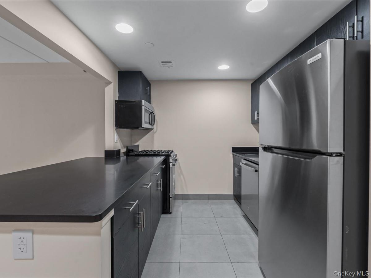 1810 3rd Avenue, Unit A2D Manhattan, NY 10029 - Photo 5 of 19 Kitchen with stainless steel appliances, dark cabinetry, recessed lighting, light tile patterned floors, and modern cabinets