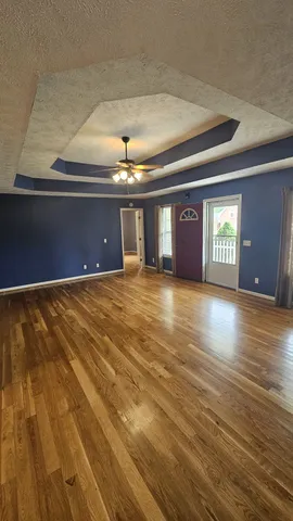 a view of an empty room with window and wooden floor