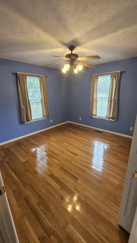 a view of an empty room with window and wooden floor