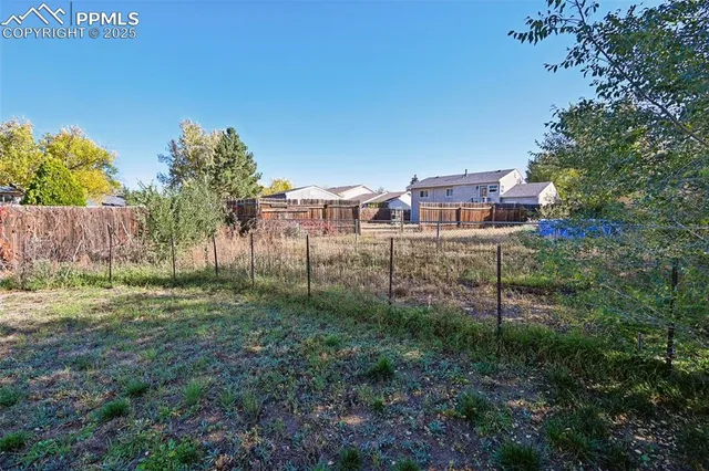 a view of a yard with plants and wooden fence