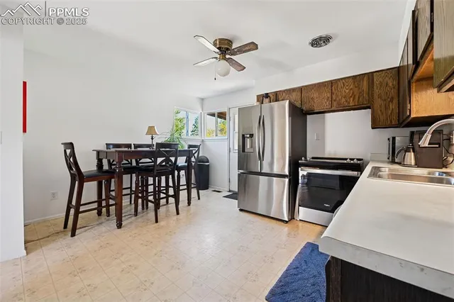 a kitchen with stainless steel appliances a refrigerator a stove a sink a dining table and chairs with wooden floor