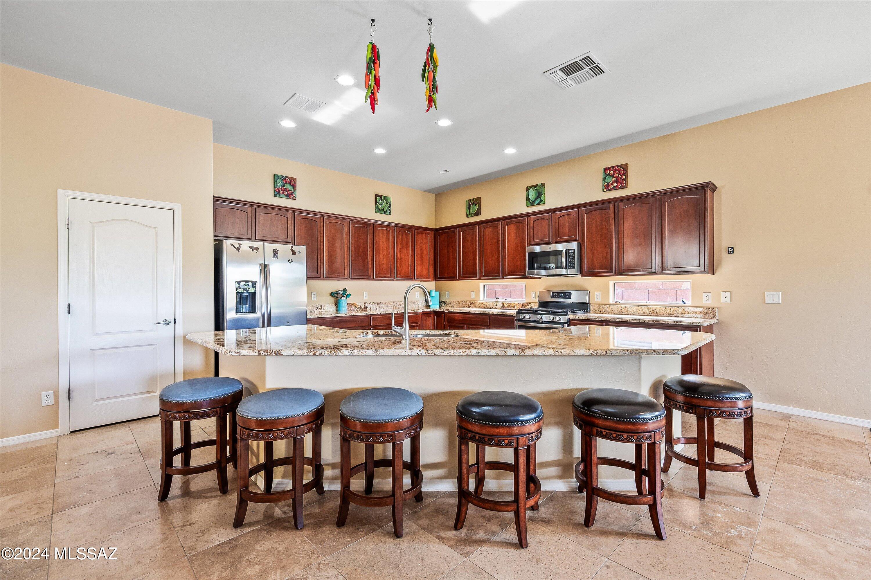 8579 North Shadow Wash Way Tucson, AZ 85743 - Photo 7 of 34 a kitchen with granite countertop a table chairs stove and cabinets