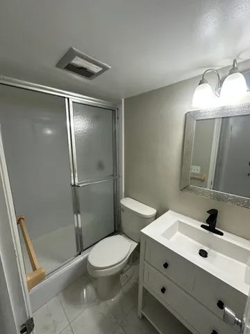 a bathroom with a double vanity sink toilet mirror and shower