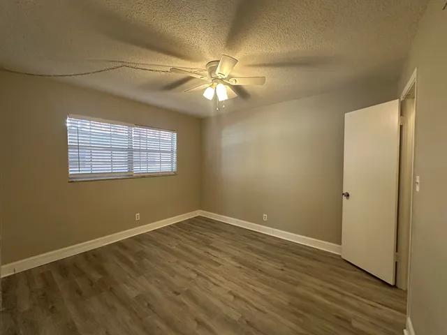 an empty room with windows and fan