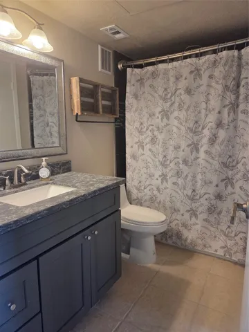 a bathroom with a granite countertop sink a toilet and a mirror