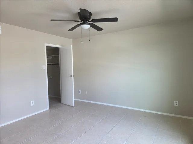 an empty room with a ceiling fan and a window