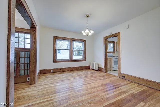 a view of an empty room with window and wooden floor