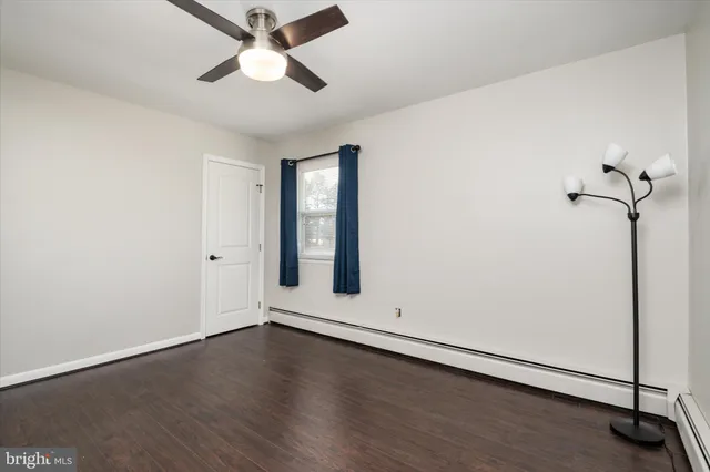 an empty room with wooden floor chandelier fan and windows