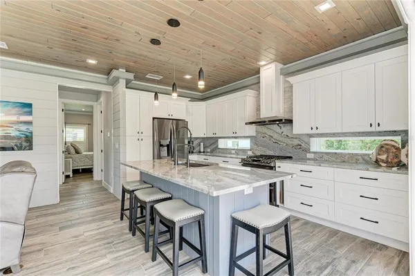 a kitchen with granite countertop a table chairs stove a sink dishwasher and cabinets with wooden floor