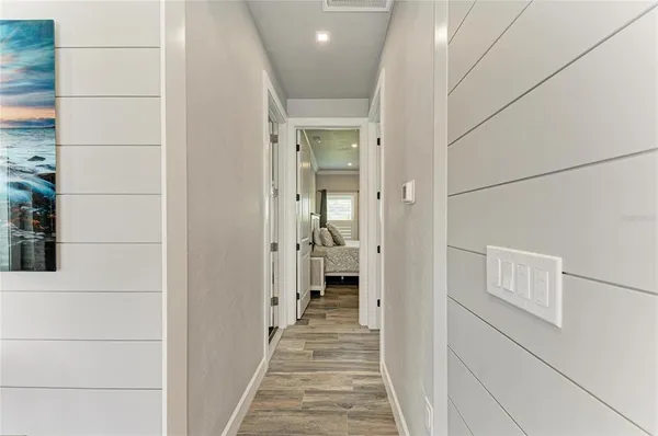 a view of a hallway with wooden floor and a bathroom